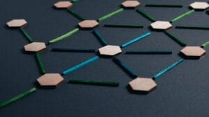Wooden hexagonal nodes linked by glowing colored lines on a dark background, forming a connected network