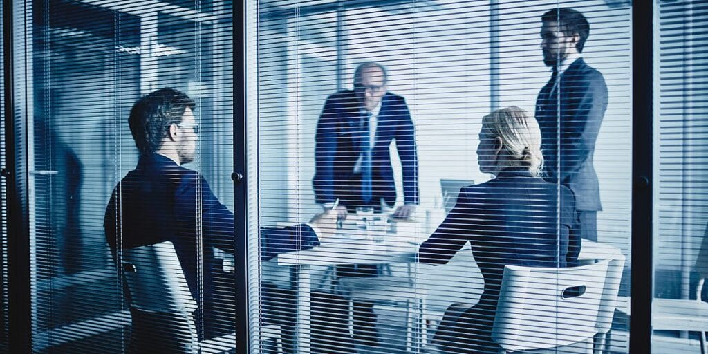 Executives Meeting Behind Glass Office Wall 1200x600 1